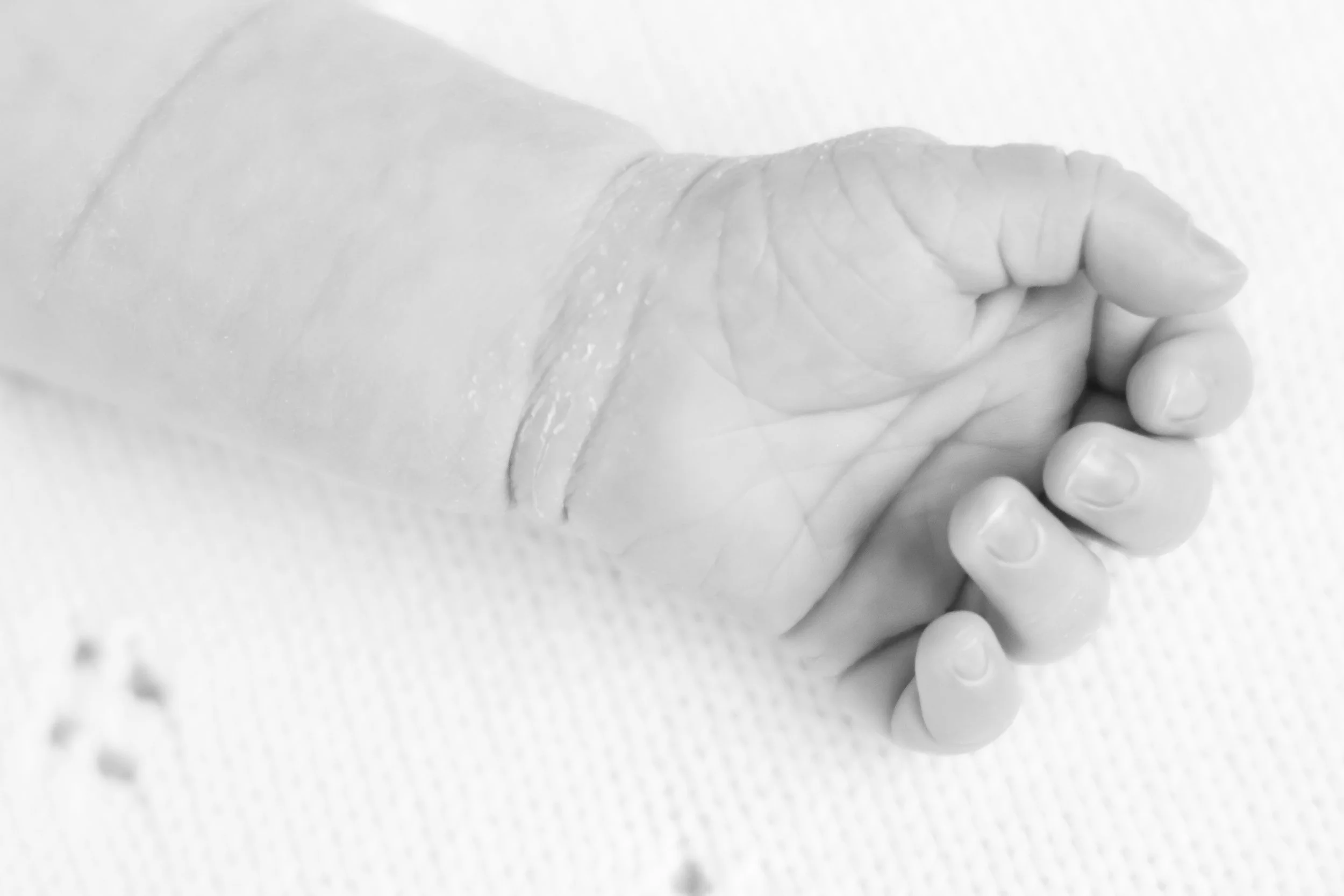 Close-up of a clenched human fist with visible knuckles and fingers, resting on a surface.