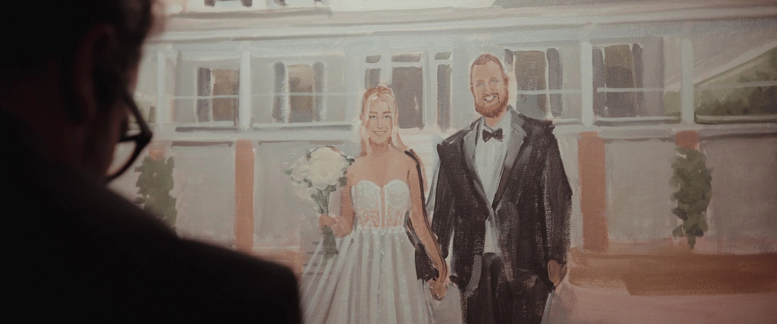 Painting of a smiling bride in a wedding dress holding a bouquet and a smiling groom in a tuxedo, standing outdoors in front of a building, with a person's profile in the foreground.