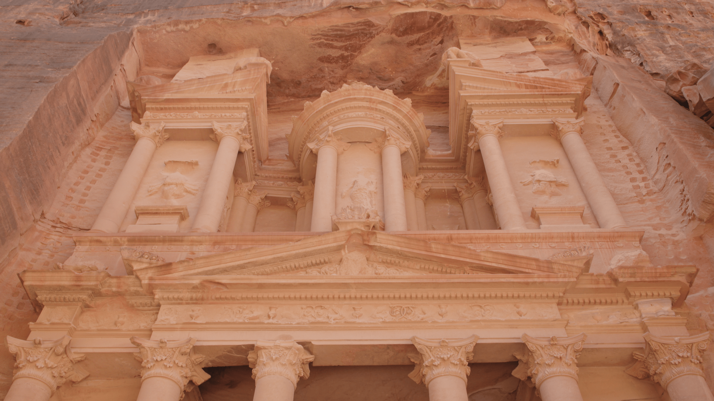 Ancient stone facade of Petra in Jordan, featuring intricate classical architectural details and columns carved into the rock.