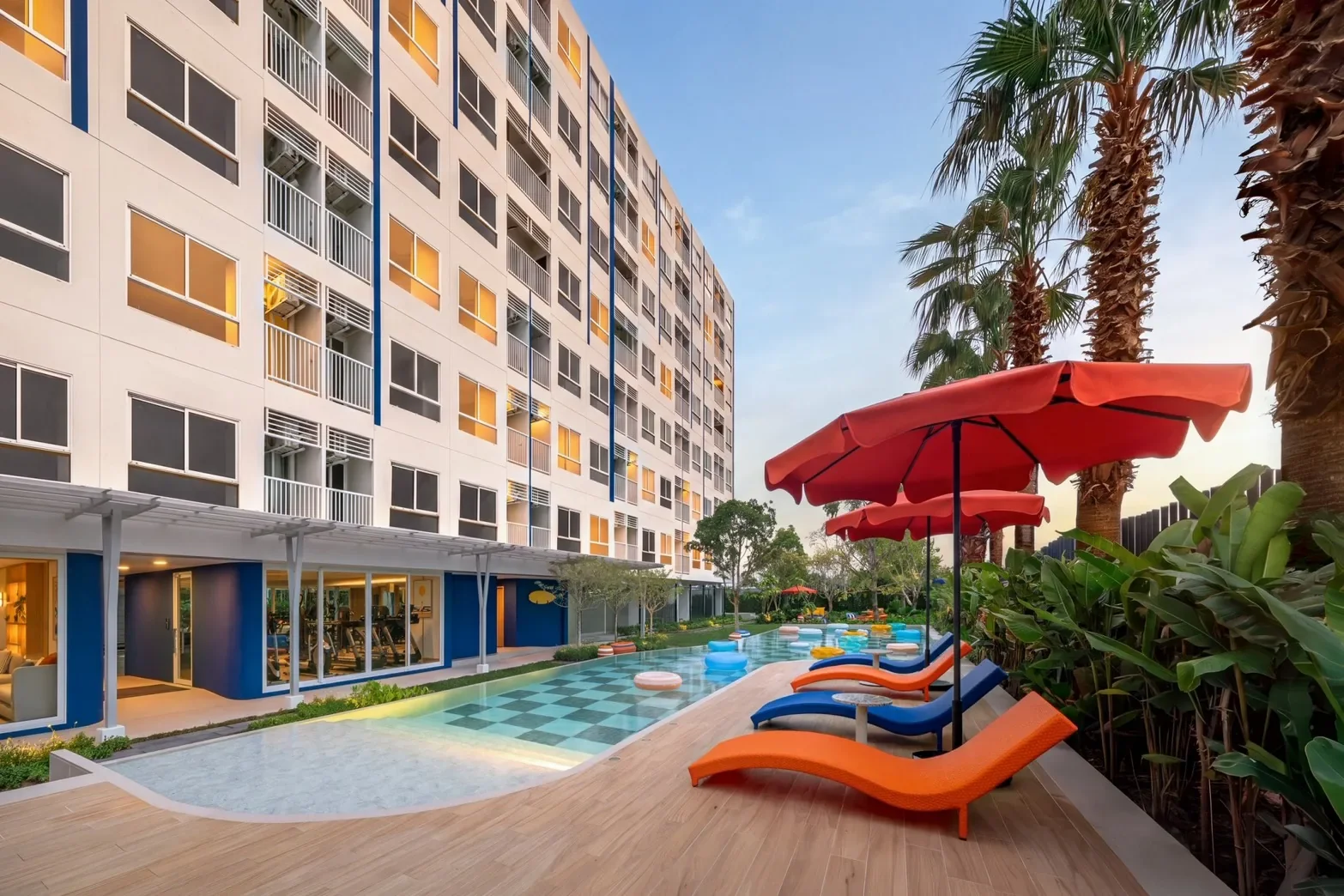 Swimming pool and condominium exterior at Hub Hua Hin with landscaped tropical gardens.