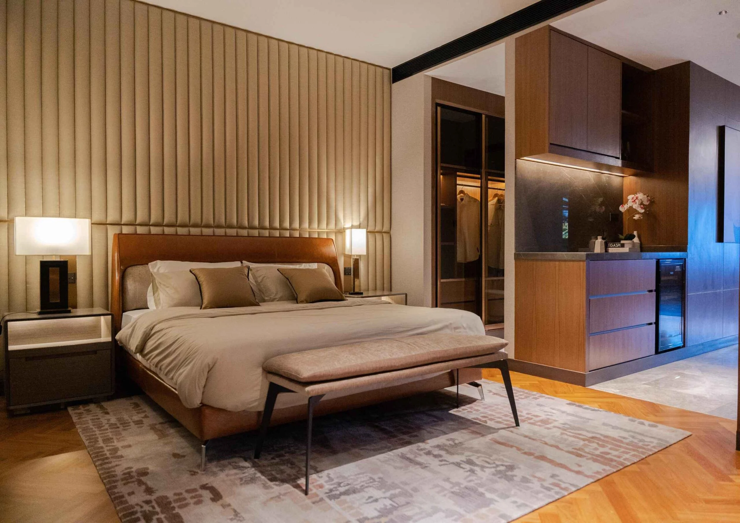Master bedroom at Orion Residence with warm lighting, soft textures, and wood furnishings.