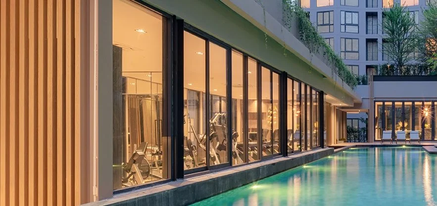 Poolside fitness centre at The Nest Sukhumvit 71, with floor-to-ceiling glass overlooking the resort-style swimming pool.