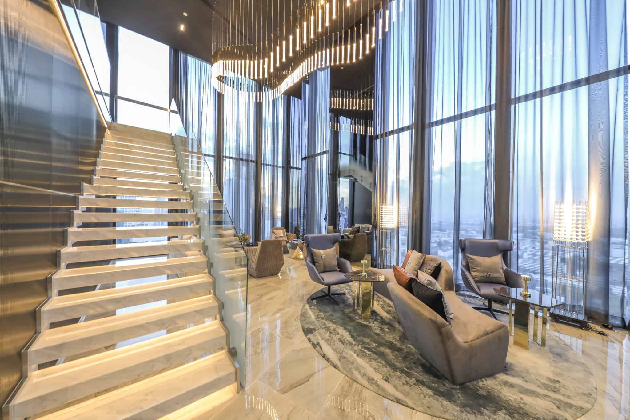 Double-height sky lounge with staircase seating area at Park Origin Phayathai.