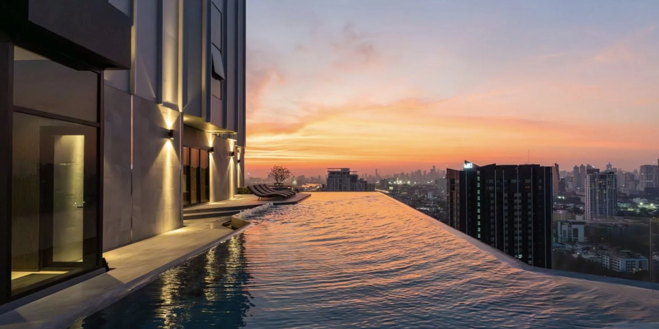 Evening view from the rooftop pool at Knightsbridge Space Sukhumvit - Rama 4, overlooking Bangkok’s skyline at sunset.