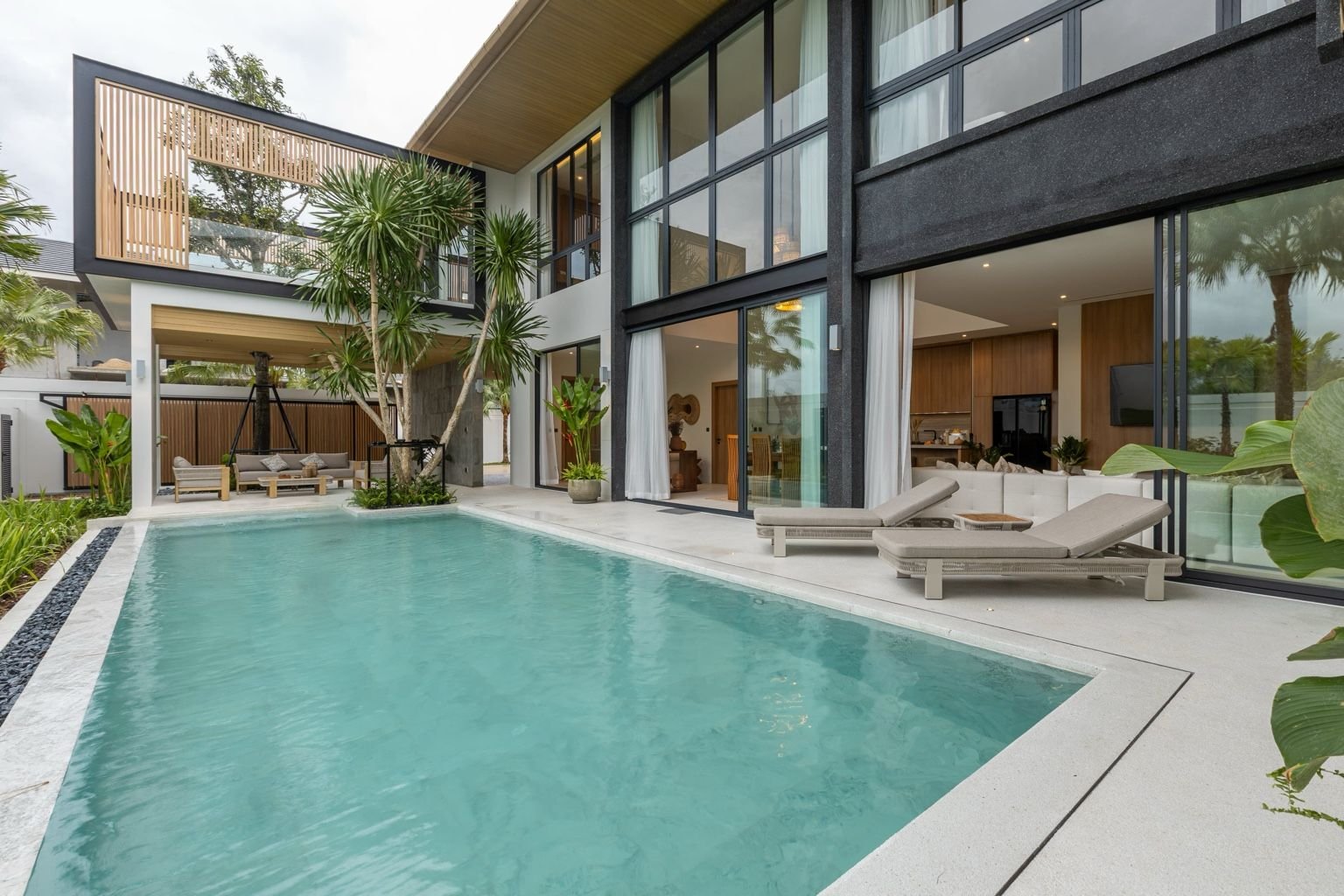 Private swimming pool at Mouana Grande Chalong Bay villa surrounded by palm trees and sun loungers.