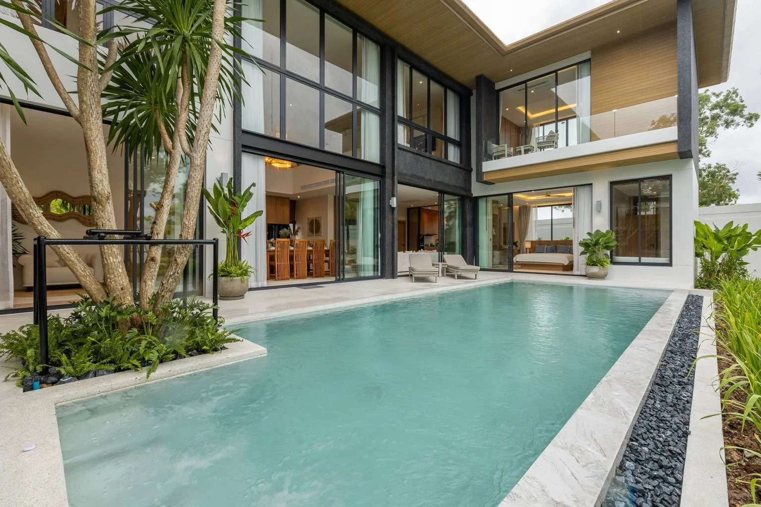 Infinity-edge pool area of Mouana Grande villa overlooking the greenery of Chalong Bay.