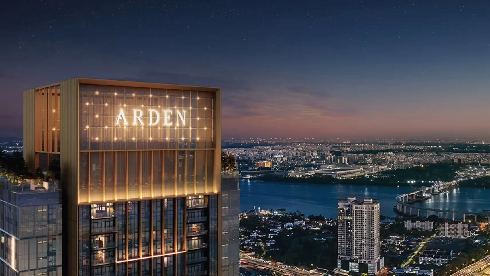 Exterior view of The Arden Johor Bahru serviced residences at night, featuring the illuminated Arden logo and panoramic city and river views.