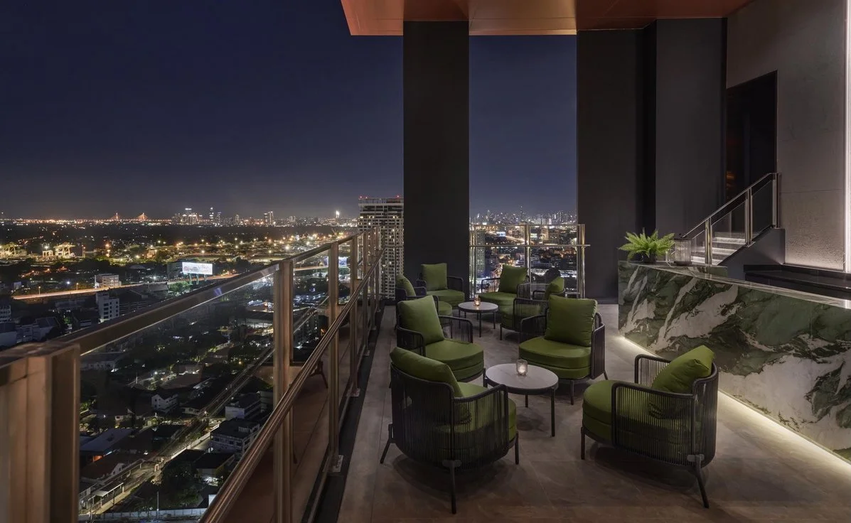 Rooftop lounge at Ideo Sukhumvit-Rama 4 with panoramic night views over Bangkok skyline and modern outdoor seating.