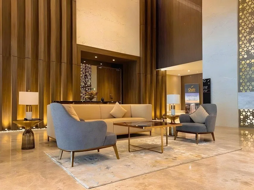 Reception area at Quill Residences with artistic wall design, chandelier lighting, and marble flooring.