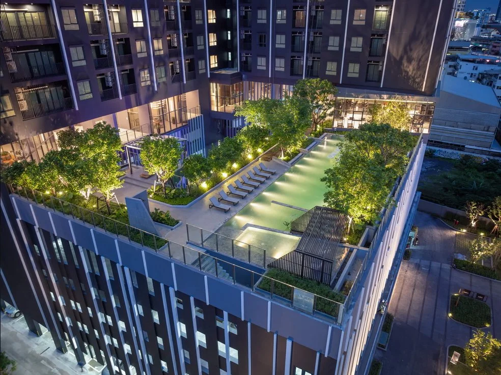 Elevated swimming pool at Ideo Sukhumvit-Rama 4 surrounded by landscaped greenery and night lighting, offering a private urban oasis.