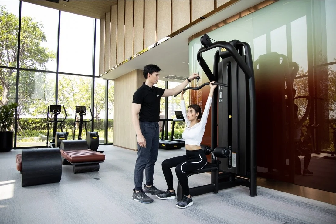 Spacious fitness centre at Coco Parc Bangkok with modern equipment, floor-to-ceiling windows, and personal training support.