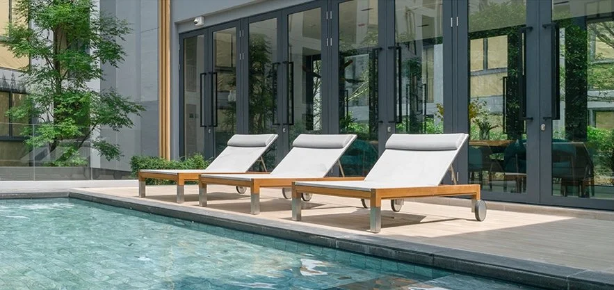 Sun loungers beside the pool at The Nest Sukhumvit 71, offering a tranquil space for residents to relax in the landscaped common area.