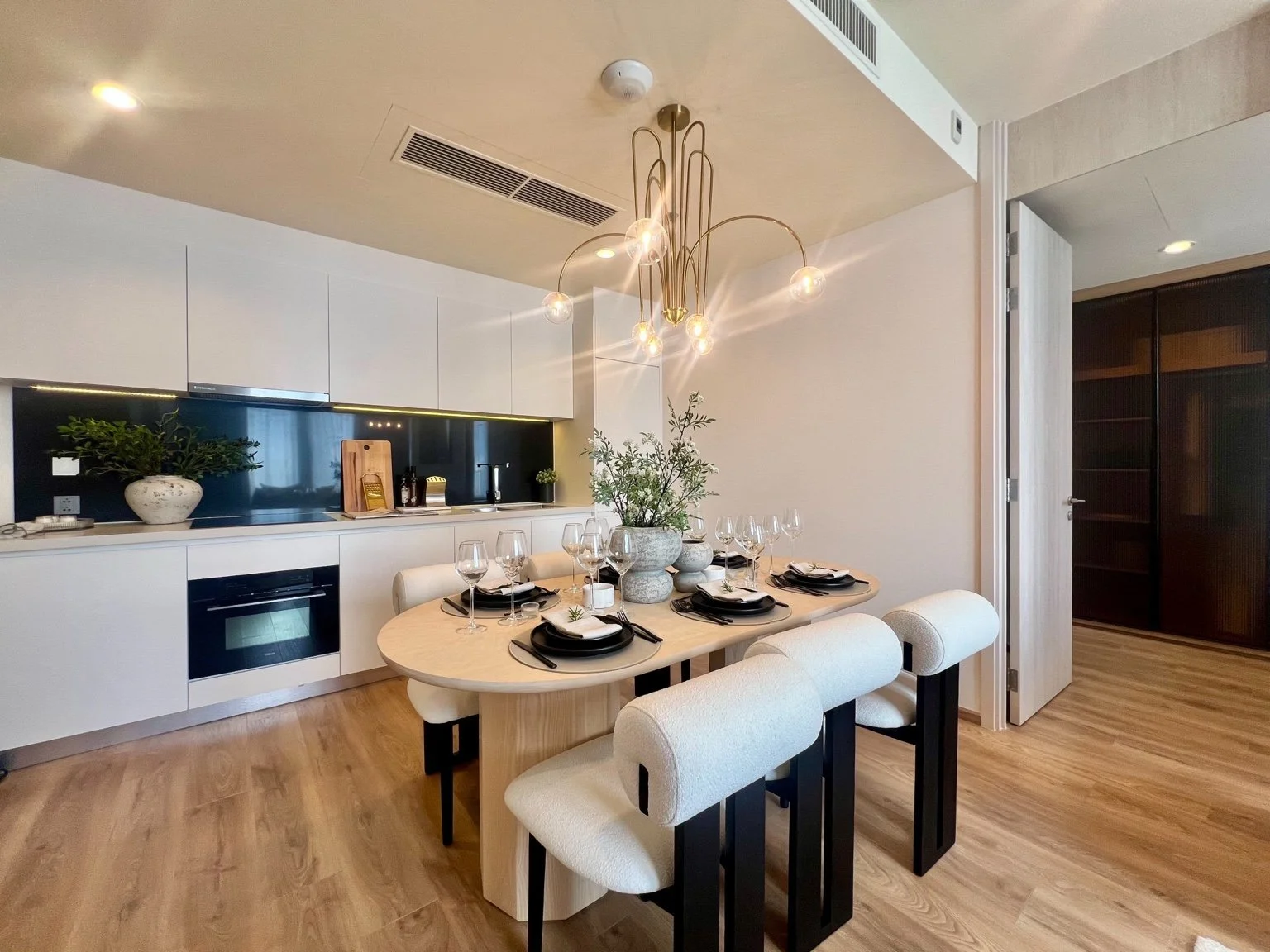 Modern dining area and kitchen at Noble Form Thonglor with fitted cabinetry and lighting.