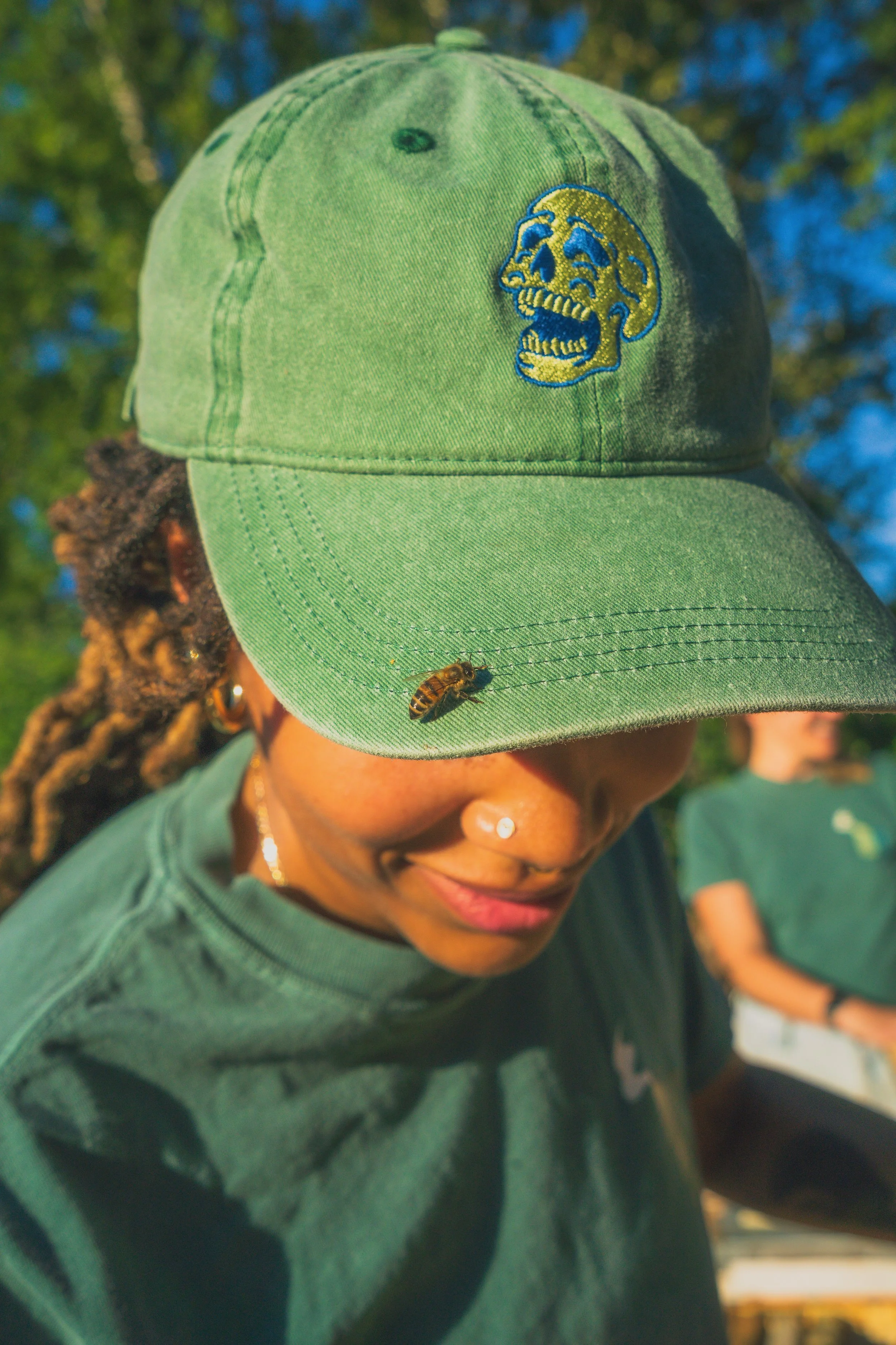 Close-up of honey bees on a hive cover with hole, surrounded by beeswax structures and a paper on the side.