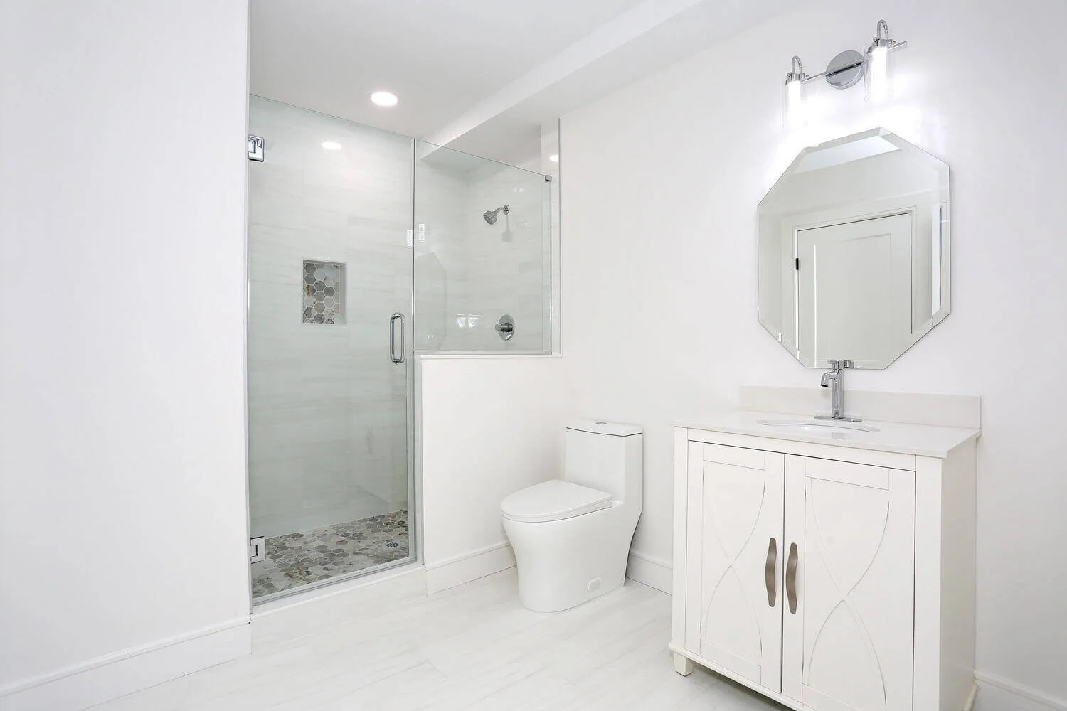 Lower level bathroom featuring a glass-enclosed shower, modern white vanity, and chrome fixtures in a Park Ridge modern farmhouse by Dadak LLC.