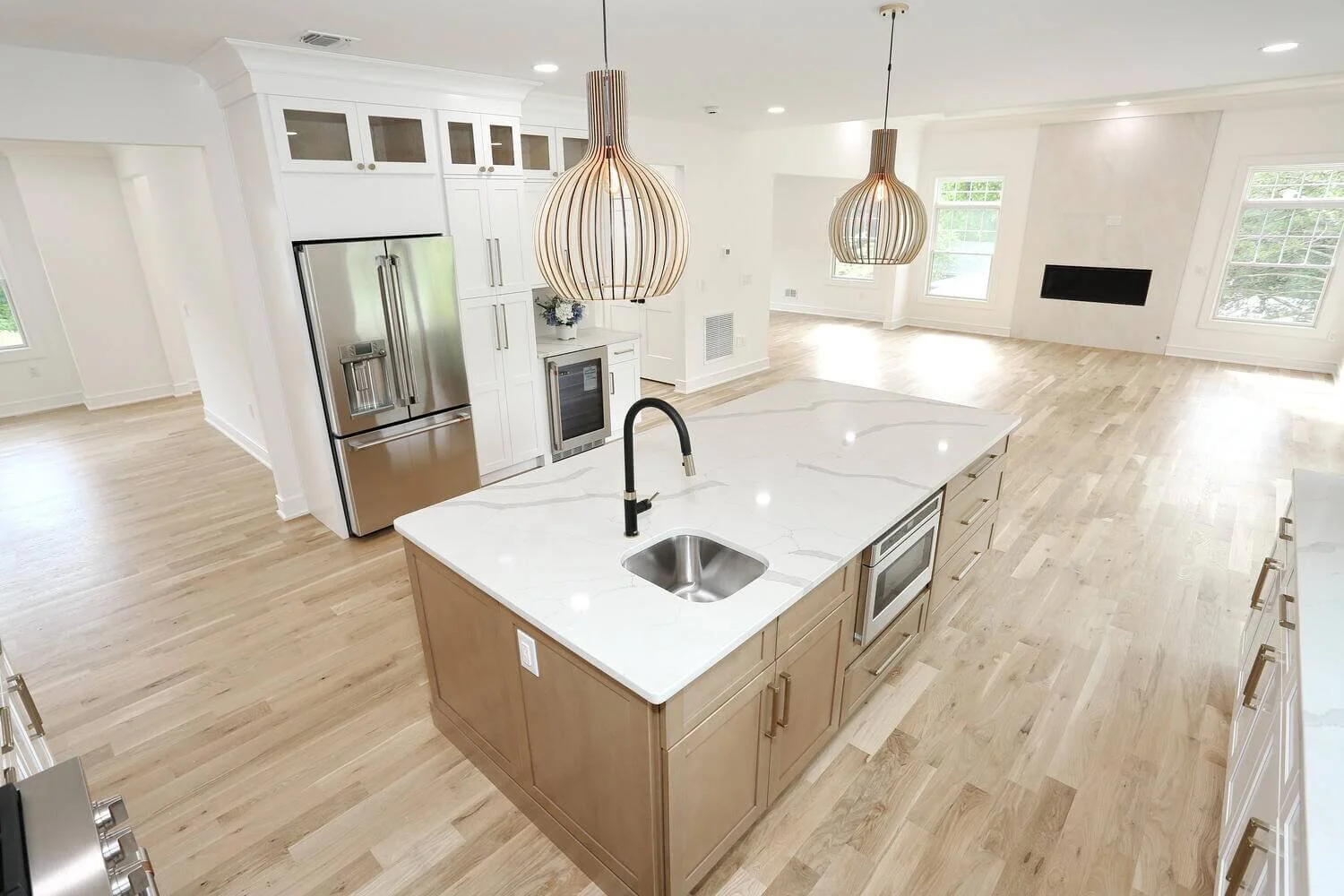 Overhead view of kitchen island with quartz countertop, pendant lights, and open layout in a modern farmhouse by Dadak LLC, Park Ridge, NJ.