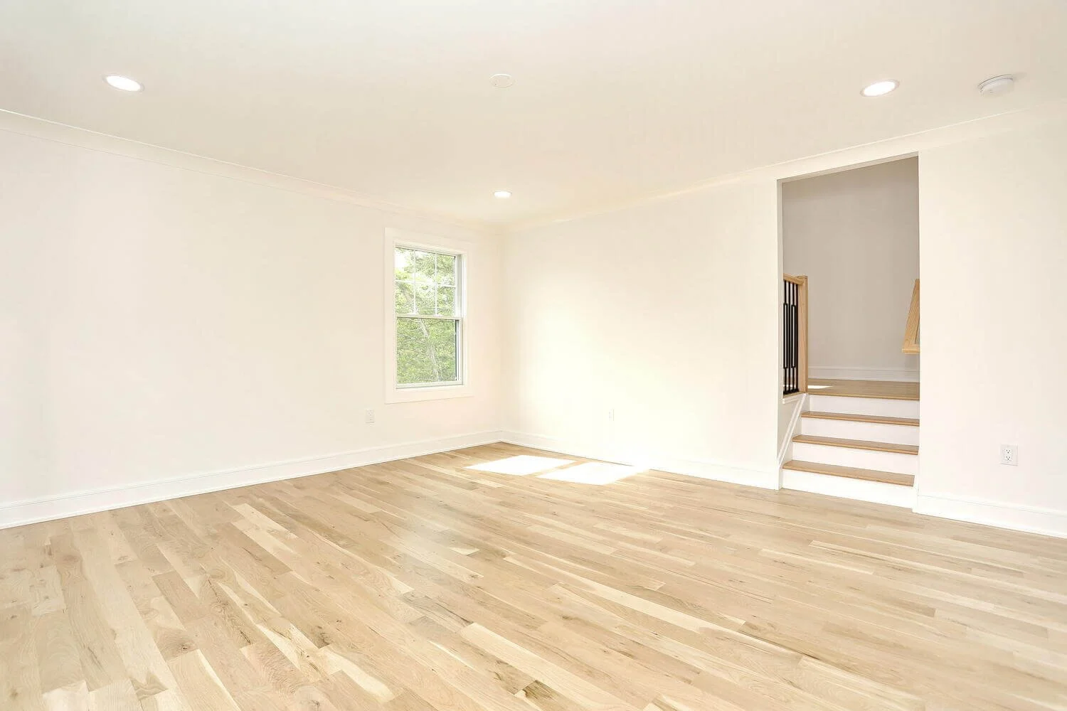 Open bedroom layout with natural wood floors and bright white walls in a Park Ridge modern farmhouse by Dadak LLC.