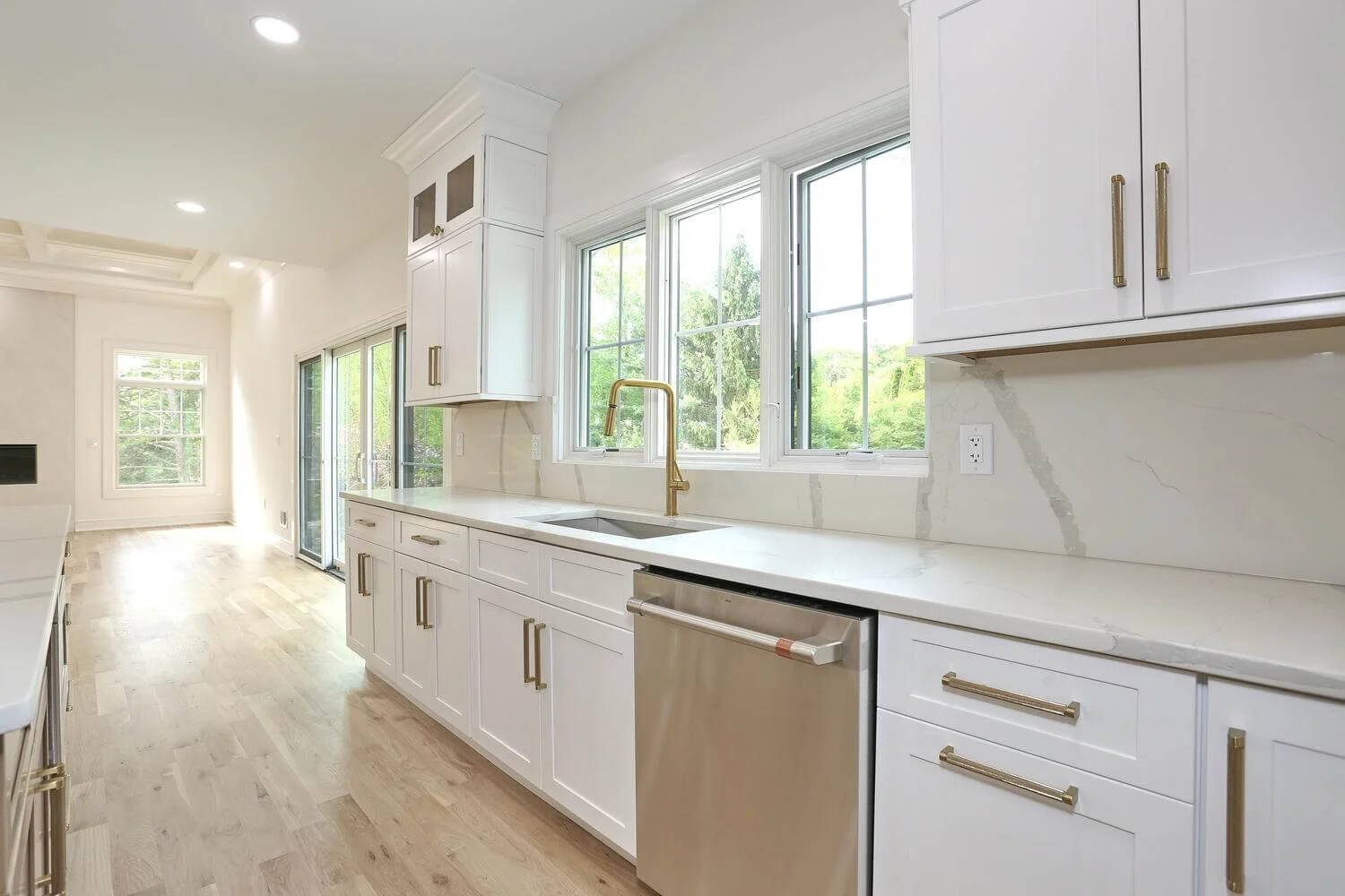 Kitchen sink with brass faucet and wide windows overlooking the backyard in a Park Ridge modern farmhouse by Dadak LLC.