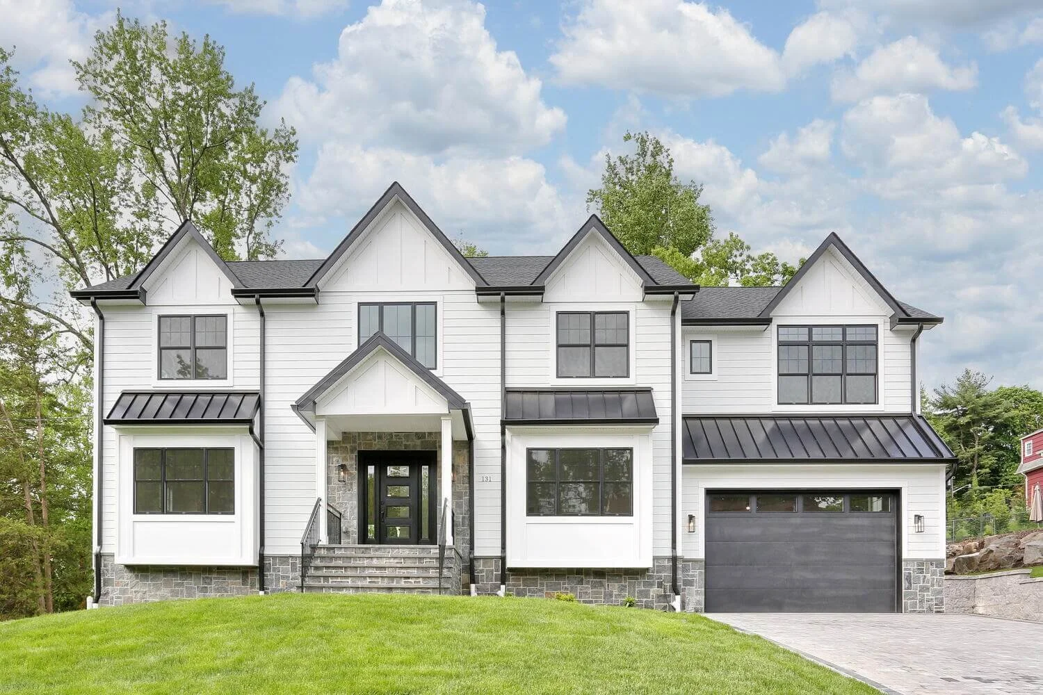 Modern farmhouse exterior built by Dadak LLC in Park Ridge, showcasing board-and-batten siding, black windows, and a stone entryway.