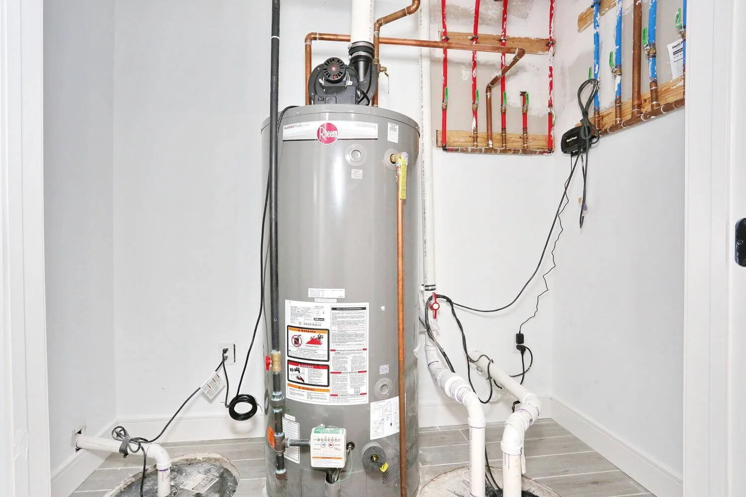 Utility room featuring Rheem water heater, sump pump system, and copper piping in a Park Ridge modern farmhouse by Dadak LLC.