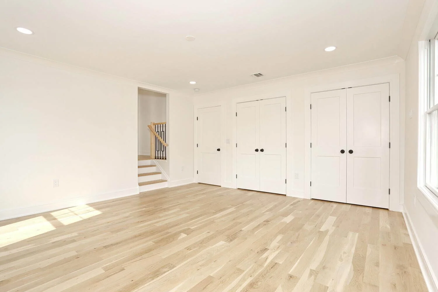 Bedroom with dual closet doors and view of open stairway with natural light in a Park Ridge modern farmhouse by Dadak LLC.