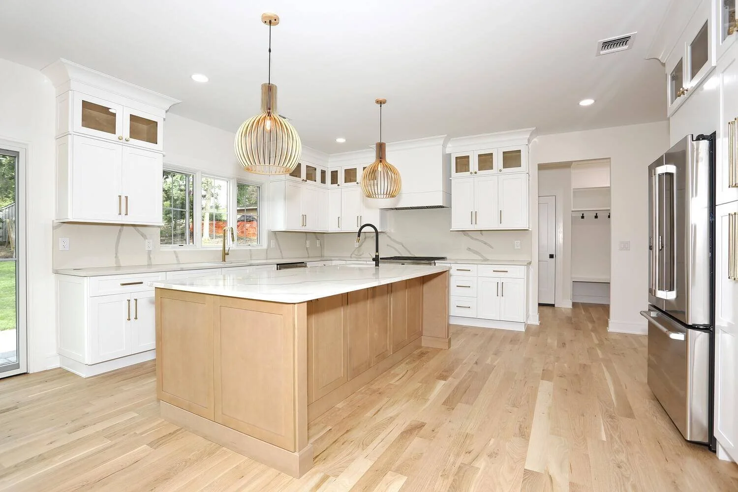 Open-concept kitchen in a Park Ridge modern farmhouse by Dadak LLC, featuring white cabinetry, wood island, quartz countertops, and pendant lighting.