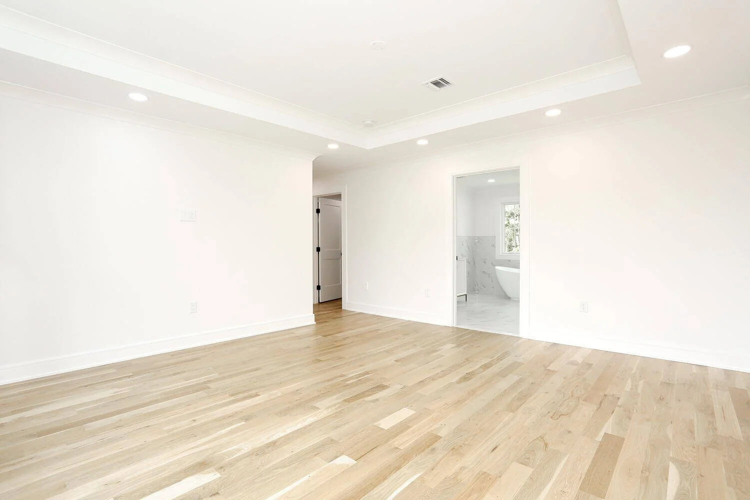 Primary bedroom featuring hardwood floors and open entry to the ensuite bathroom in a Park Ridge modern farmhouse by Dadak LLC.