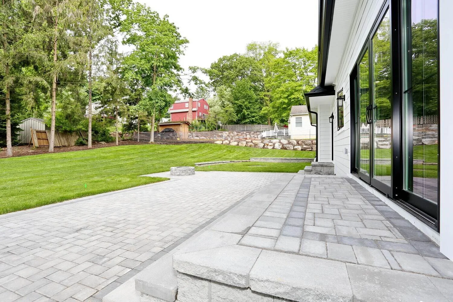 Rear patio area with double steps, sliding glass doors, and outdoor fire pit in a Park Ridge modern farmhouse by Dadak LLC.