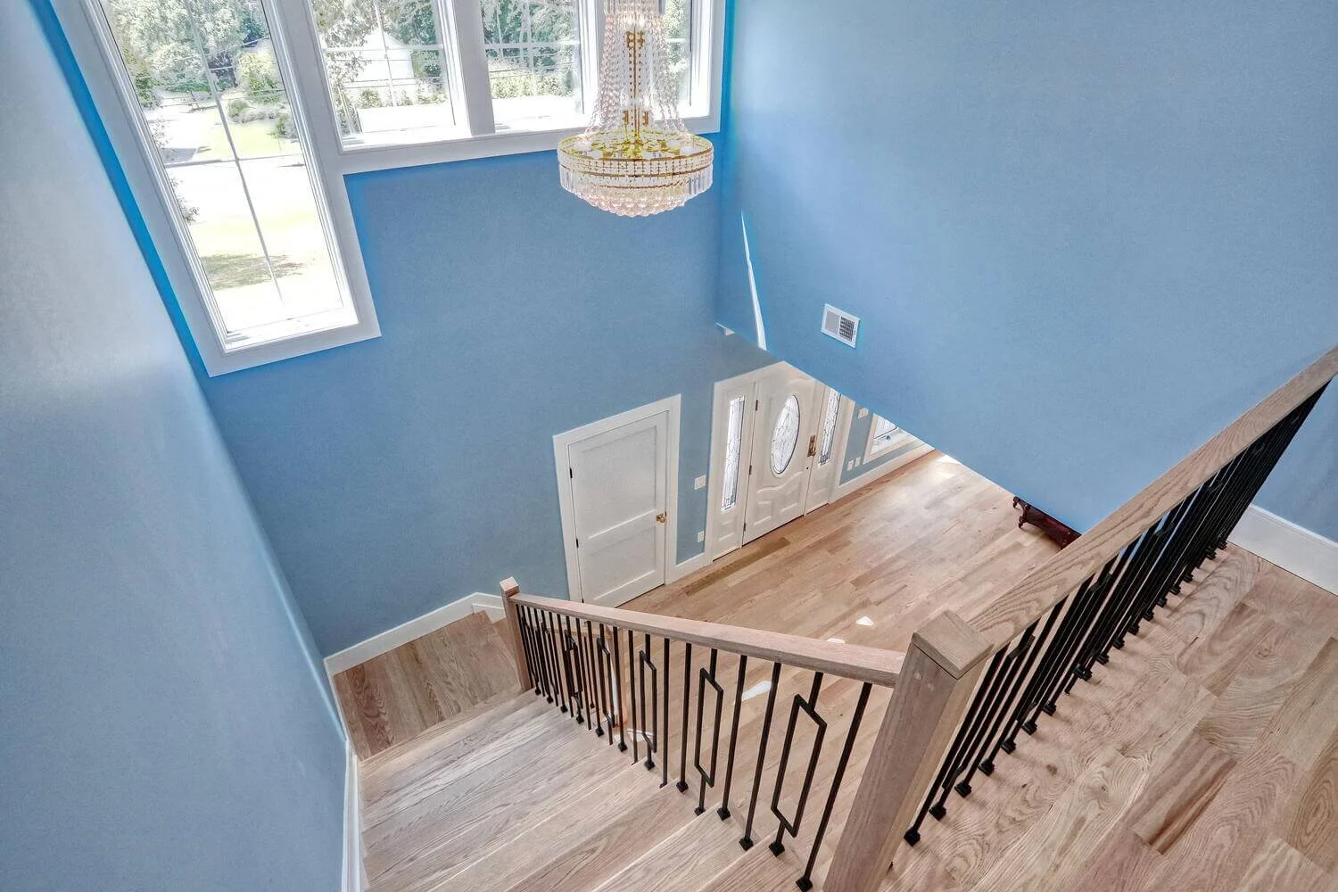 Staircase landing overlooking the foyer with chandelier and bright natural light in Montvale home.