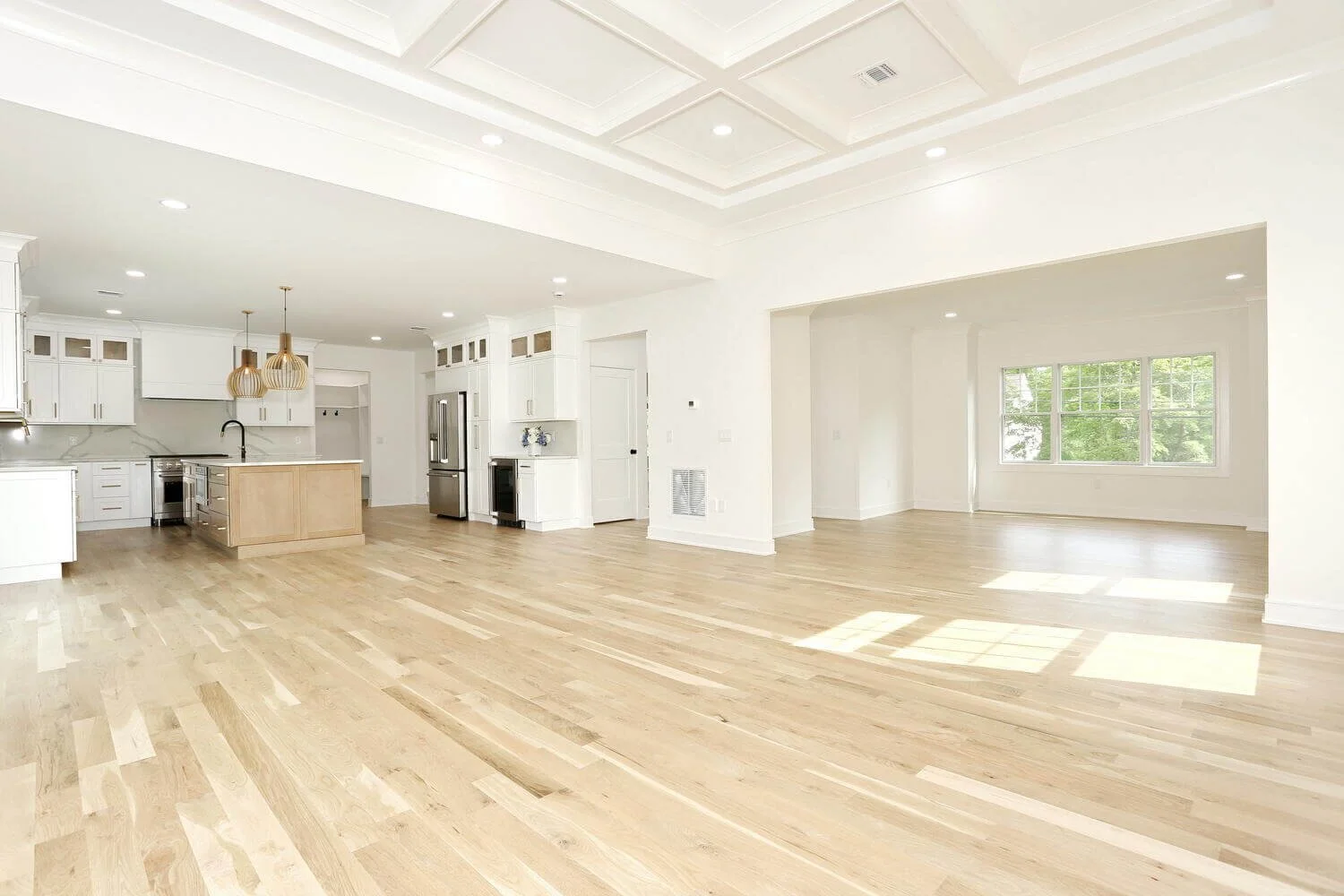 Open-concept layout showing family room, kitchen, and dining area with white cabinetry and oak flooring in a custom home by Dadak LLC, Park Ridge, NJ.