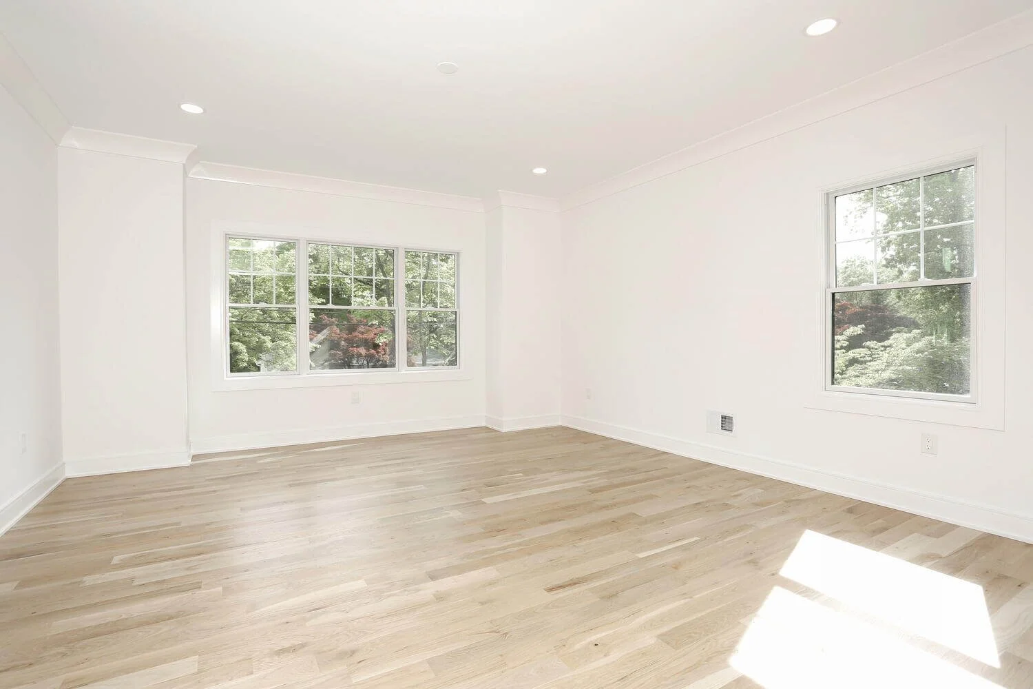 Dining room with expansive windows and light wood flooring in a custom modern farmhouse by Dadak LLC in Park Ridge, NJ.