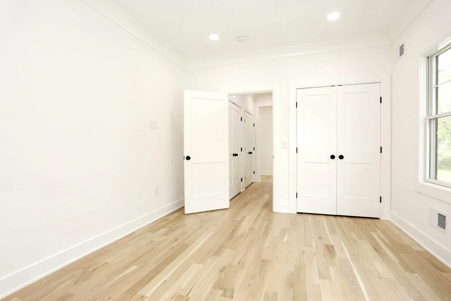 Bright bedroom with open hallway view, recessed lighting, and hardwood floors in a Park Ridge modern farmhouse by Dadak LLC.