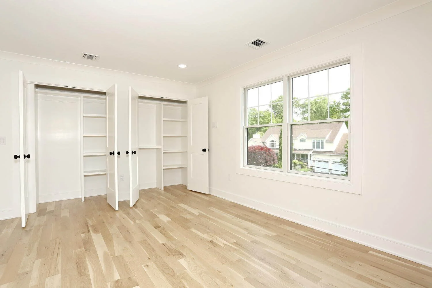 Bedroom with built-in closet shelving and large window view of the neighborhood in a Park Ridge modern farmhouse by Dadak LLC.