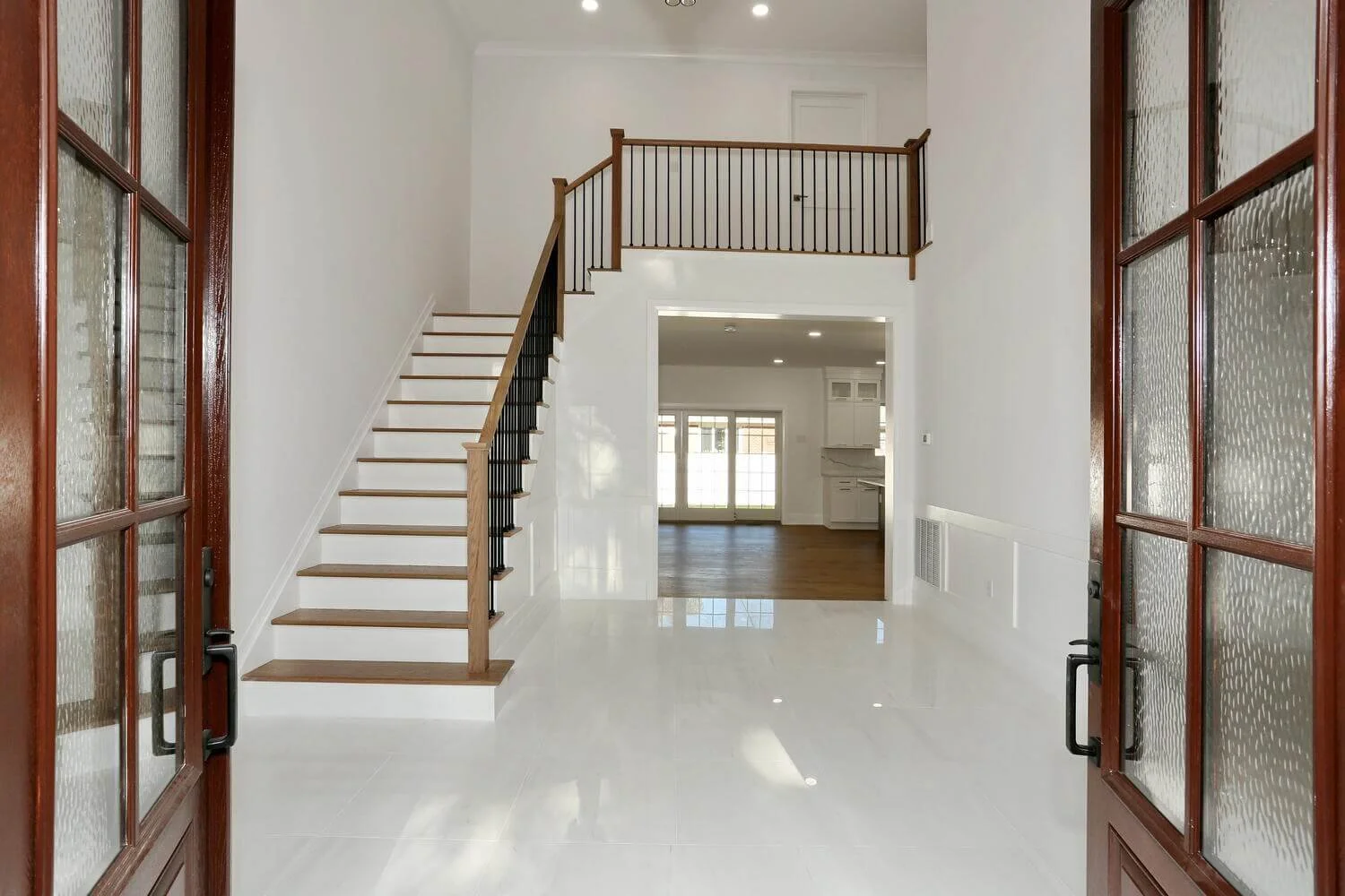 Spacious two-story foyer with hardwood staircase and modern black railing inside a custom-built home in River Vale by DADAK LLC.