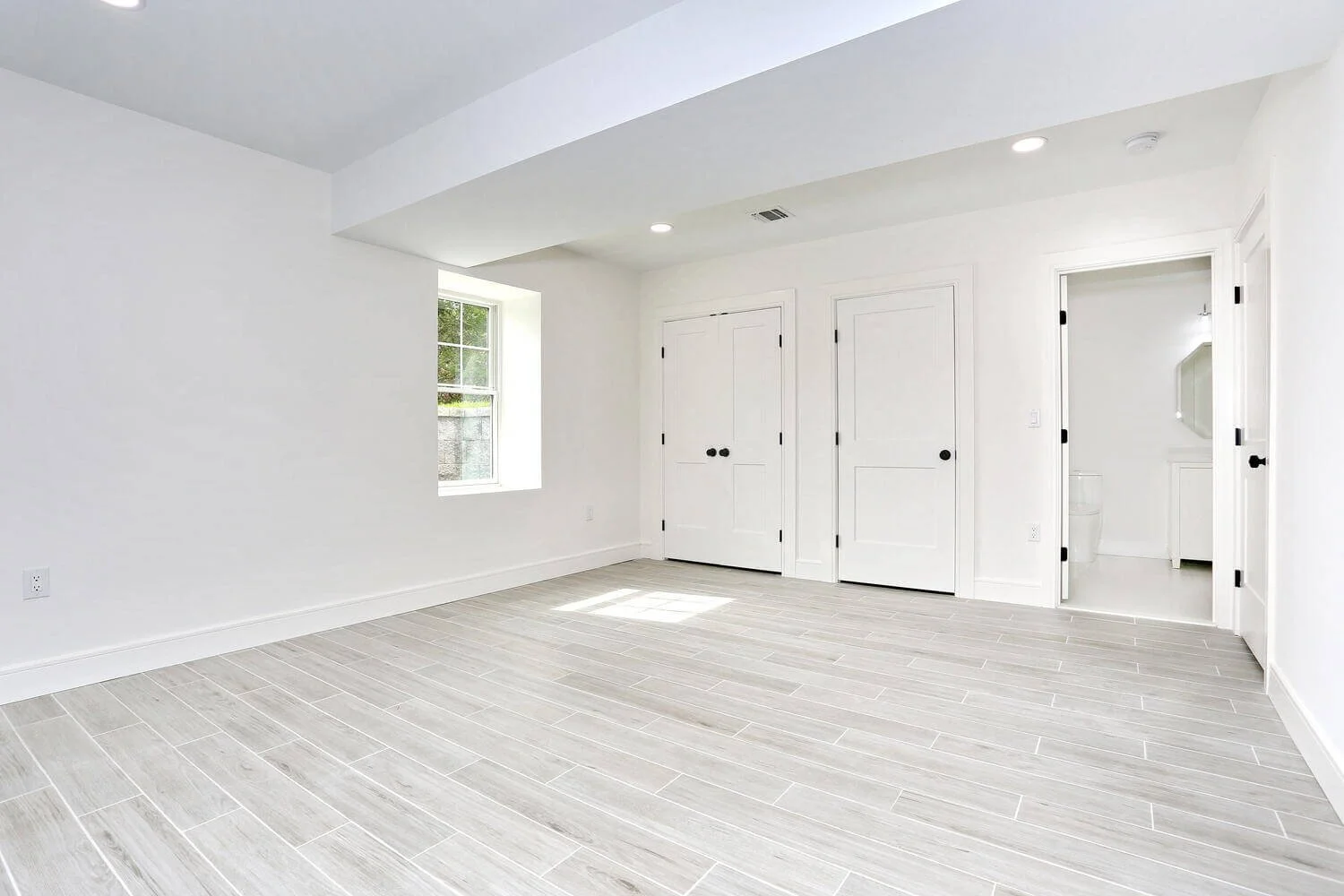 Basement bedroom with double closets, modern doors, and neutral gray tile flooring in a Park Ridge modern farmhouse by Dadak LLC.