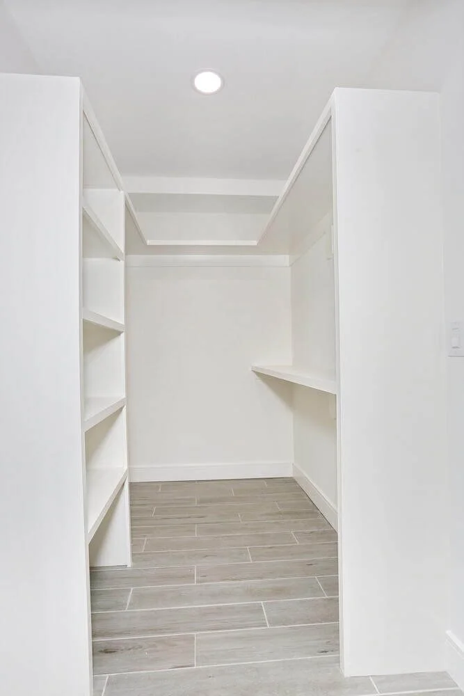 Spacious walk-in closet with built-in shelving and bright lighting in the lower level bedroom of a Park Ridge modern farmhouse by Dadak LLC.