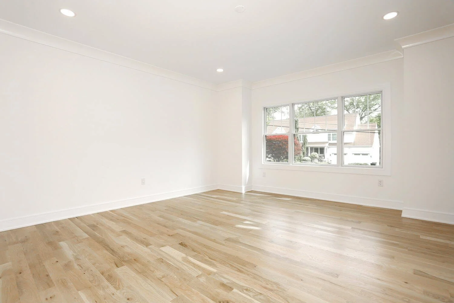 Open living room with hardwood flooring and natural light in a new construction modern farmhouse by Dadak LLC in Park Ridge, NJ.