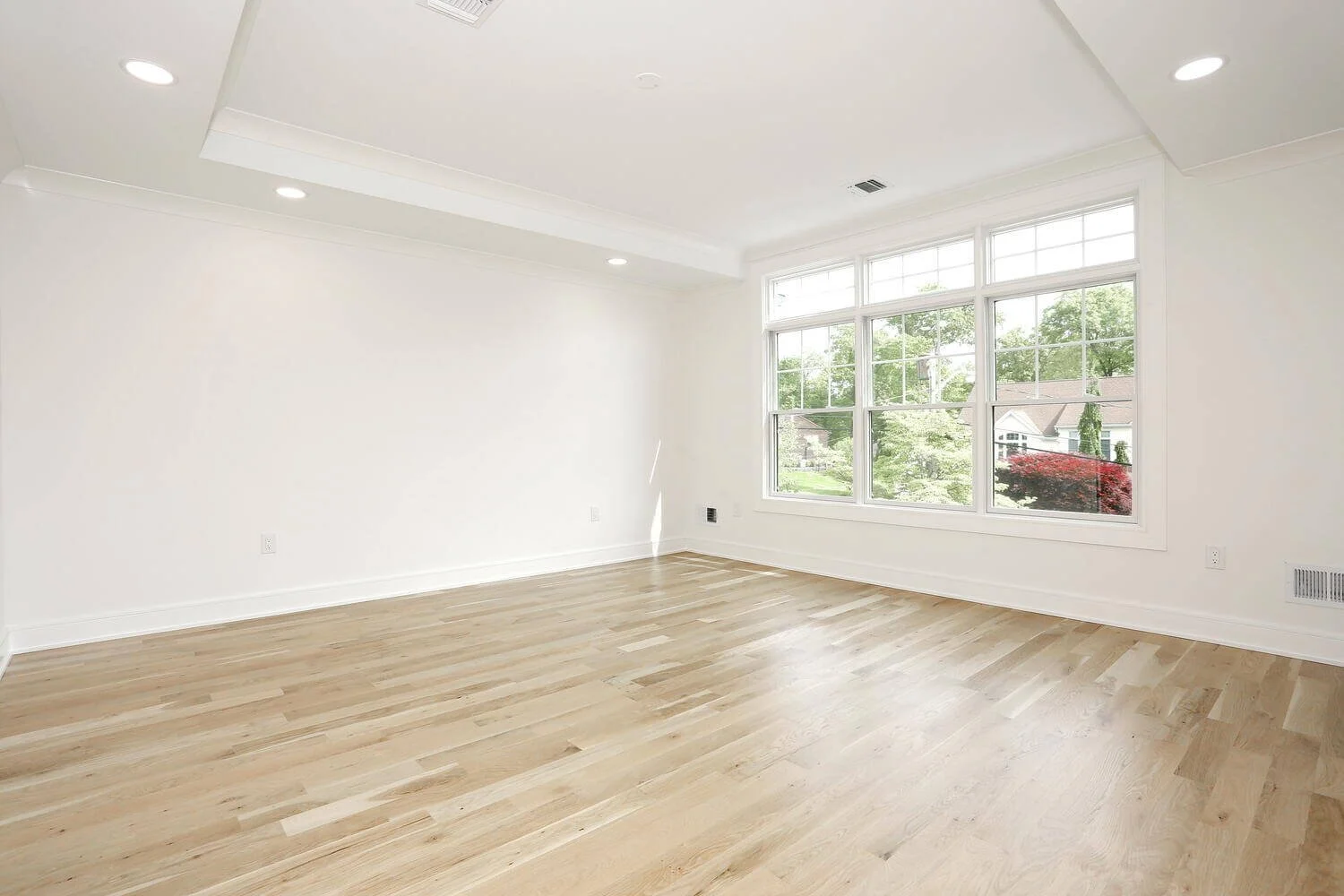 Spacious primary bedroom with large windows, recessed lighting, and light oak floors in a Park Ridge modern farmhouse by Dadak LLC.