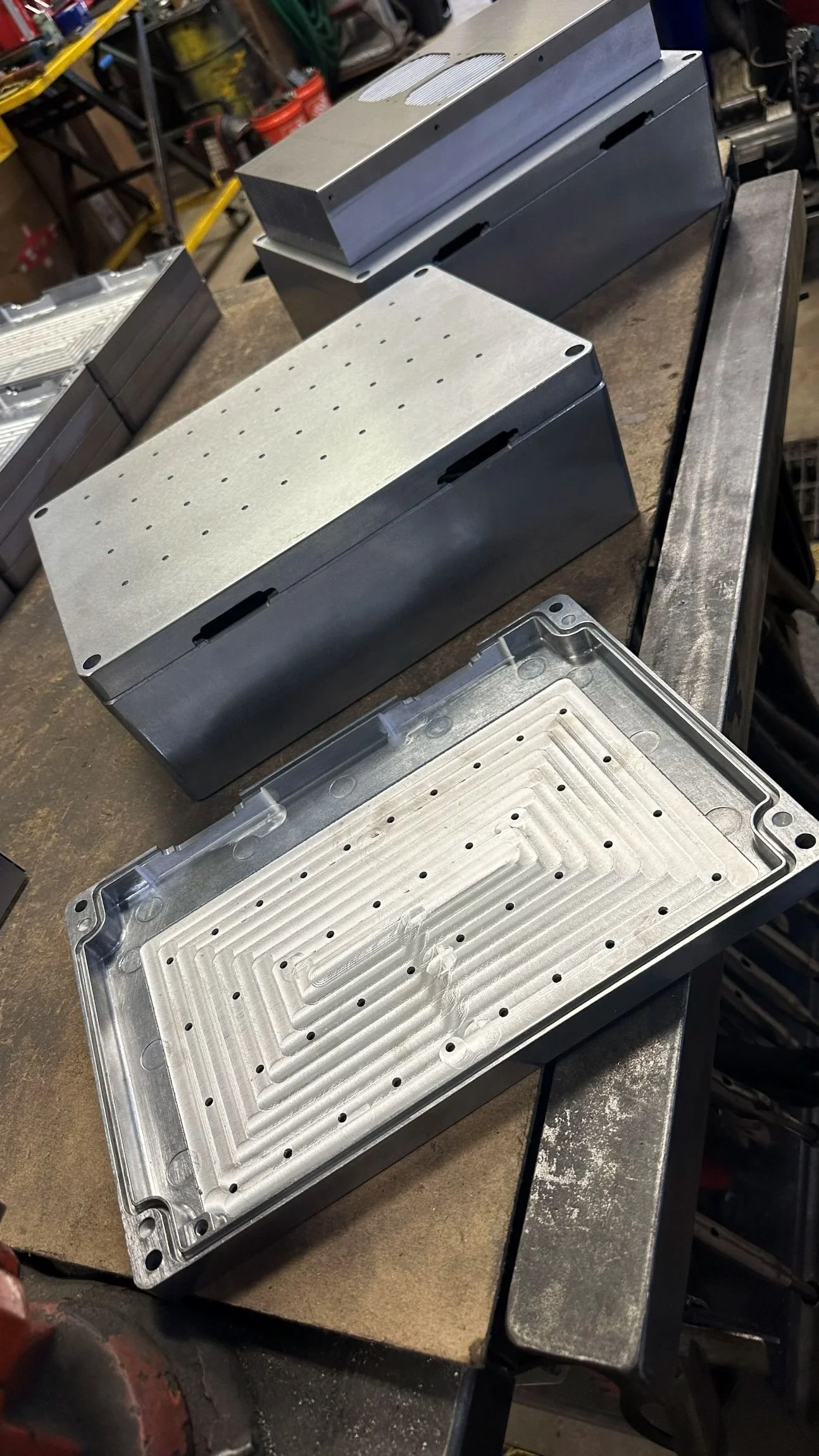 Various metal enclosures and components on a workbench in a workshop.