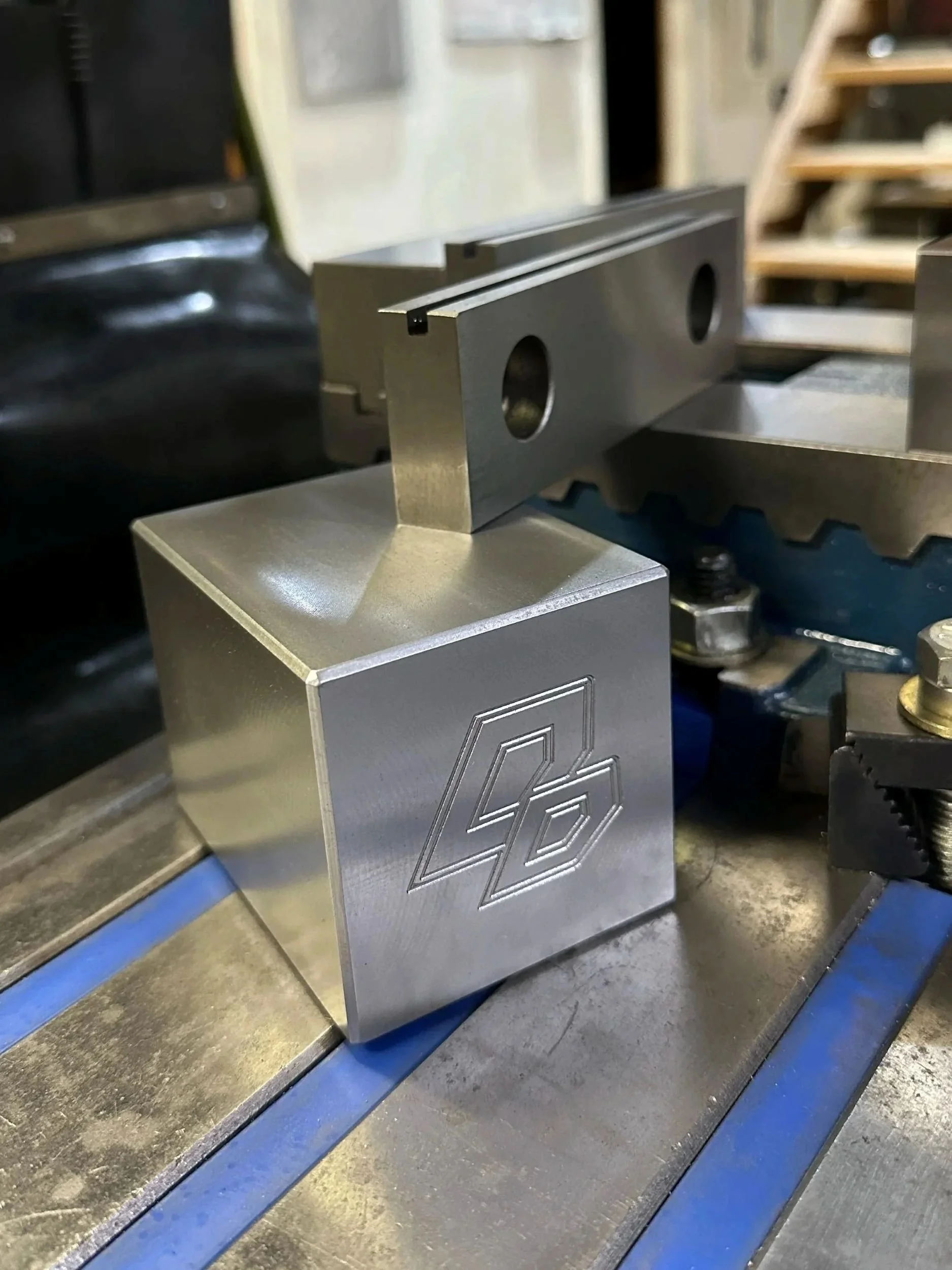 Close-up of a metallic engraved block with a geometric pattern on a workbench in a workshop.