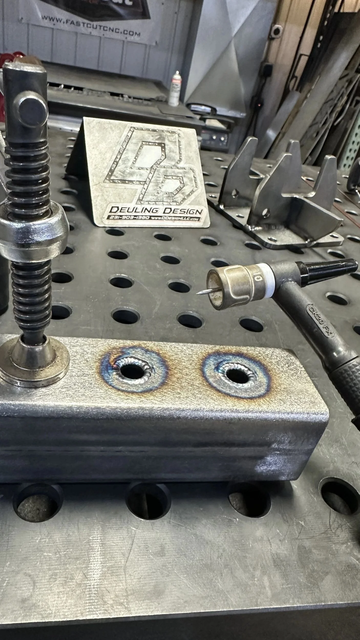 Close-up of two precision hole welds in steel, showing clean weld penetration and heat tint after welding.
