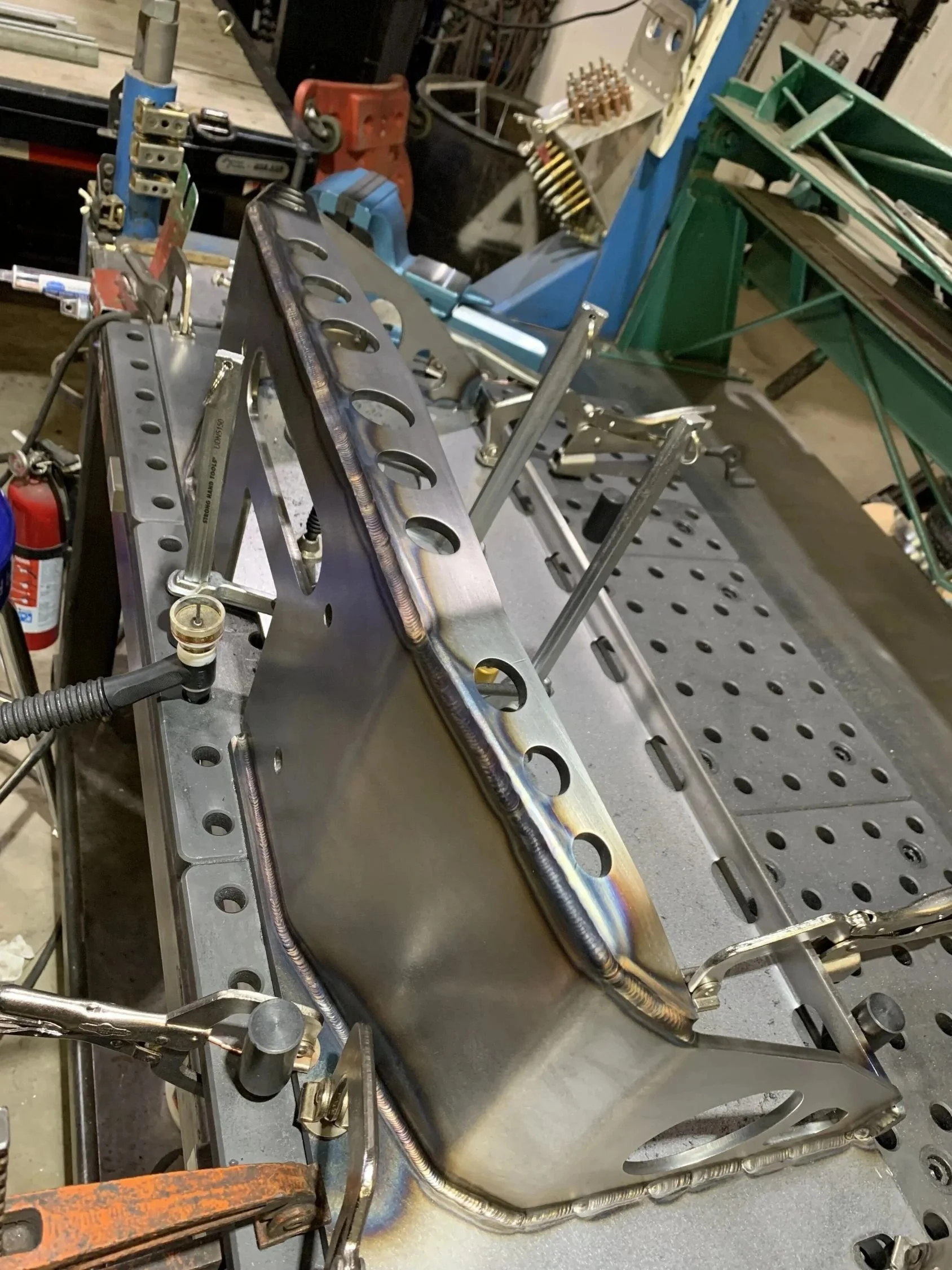 Steel component secured in a welding fixture during welding for accurate fabrication and assembly.