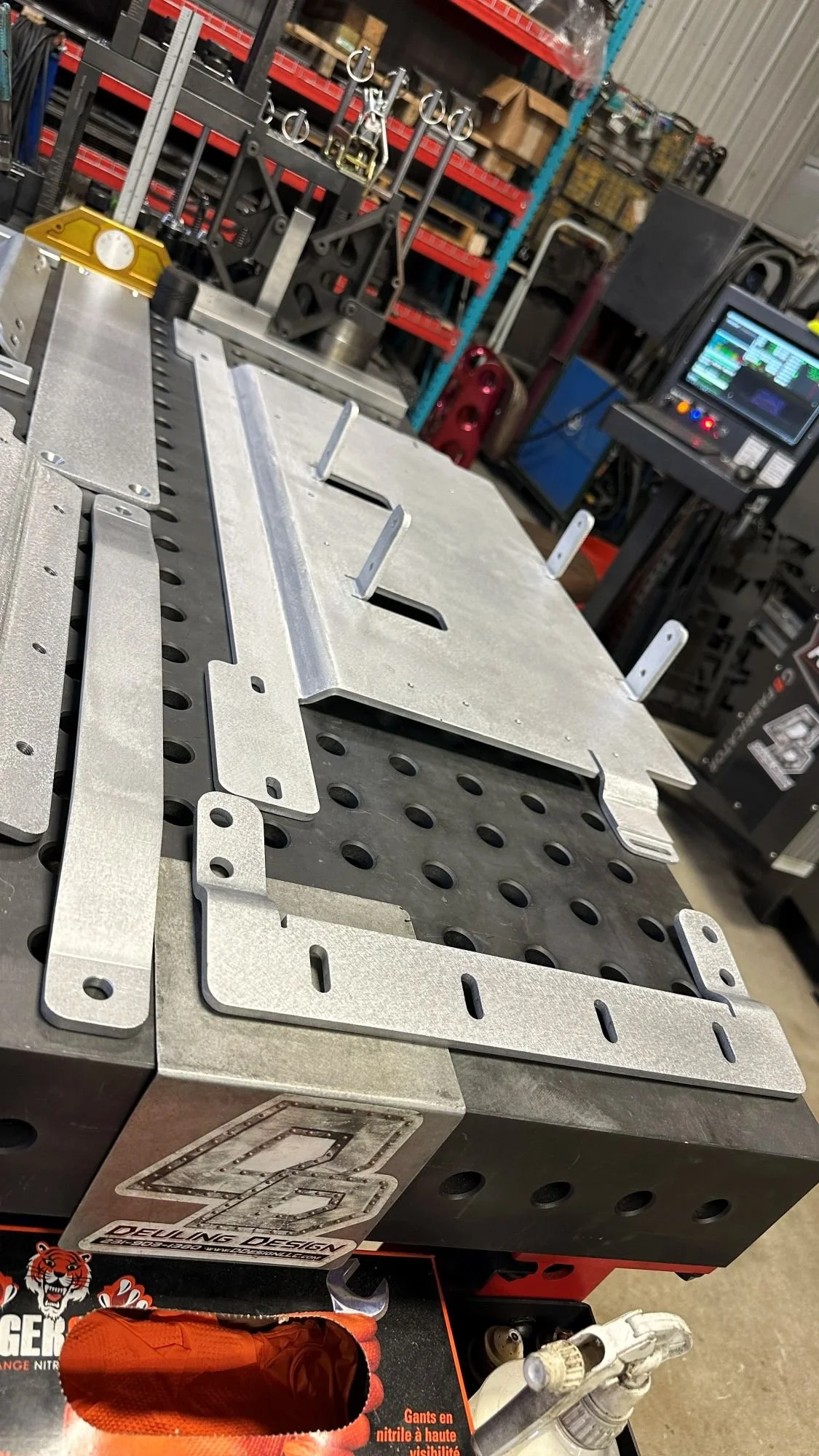1/4-inch aluminum components laid out on a perforated metal welding table.