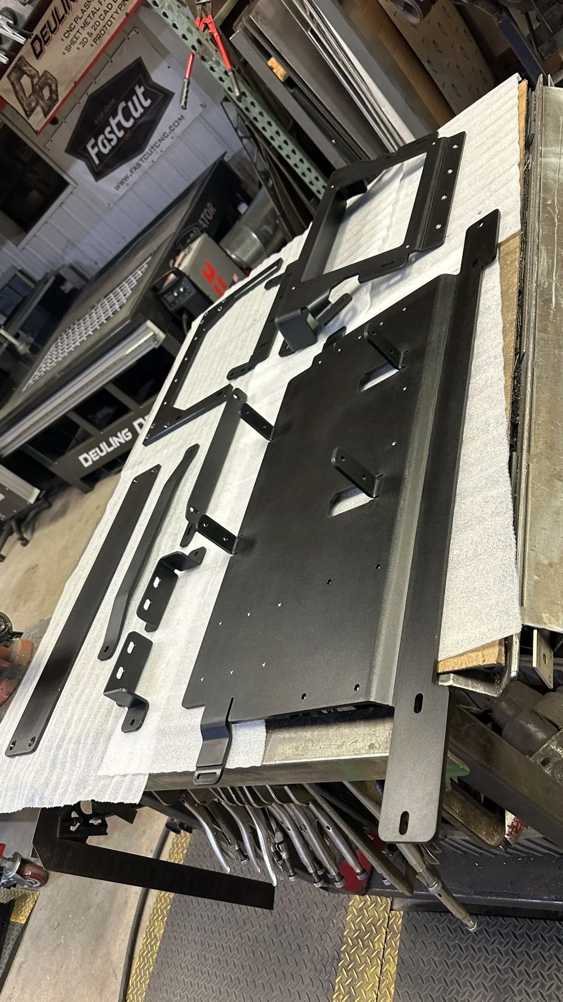 Fabricated aluminum parts with a protective black anodized finish displayed on a workshop table.