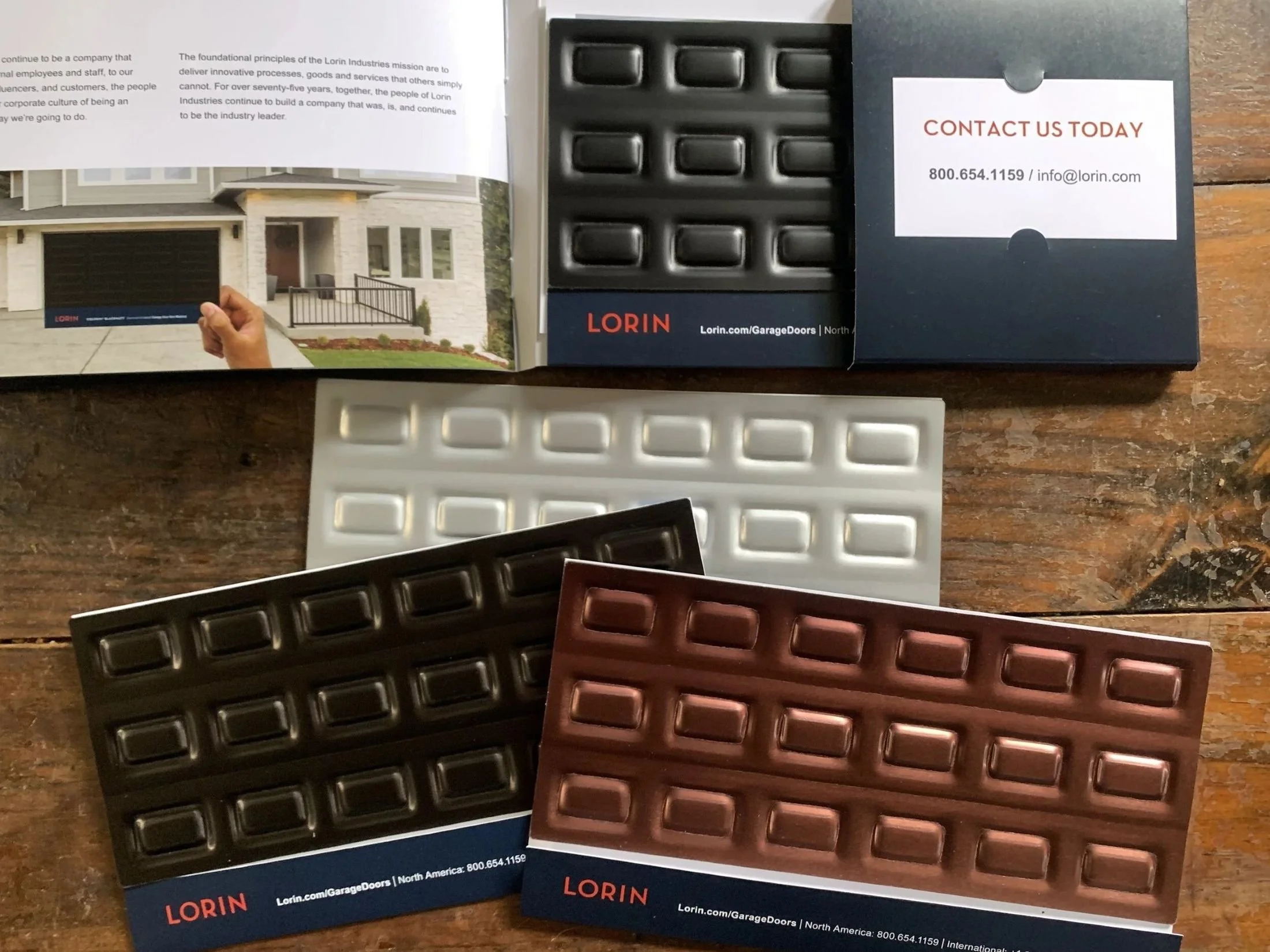 Sample cards and packaging for Lorin garage doors industry, including a promotional brochure with a picture of a modern house with a garage and contact information for Lorin.