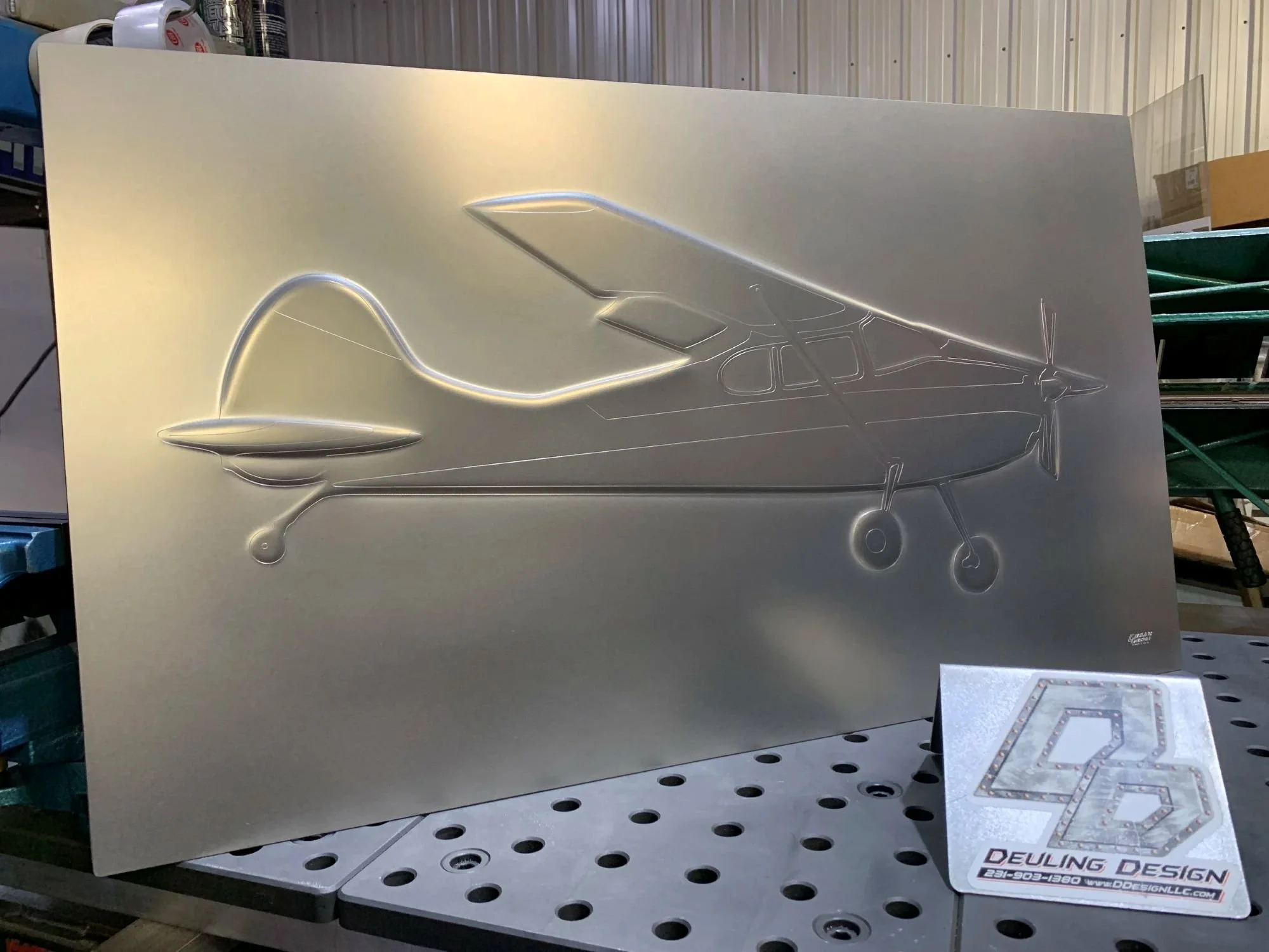 Metal sign with a bead rolled propeller airplane illustration.