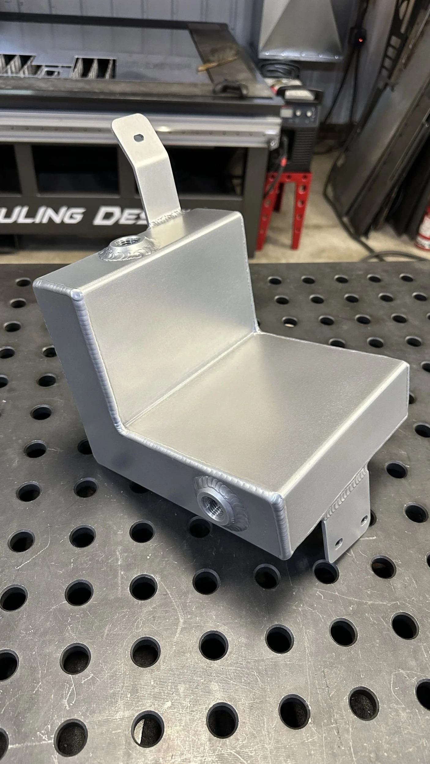 A welded metal part with a 45 degree angle, and a bracket off the top with mounting hole.
