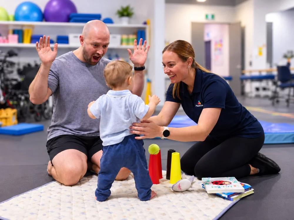 Therapist and parent encouraging a toddler to walk between them