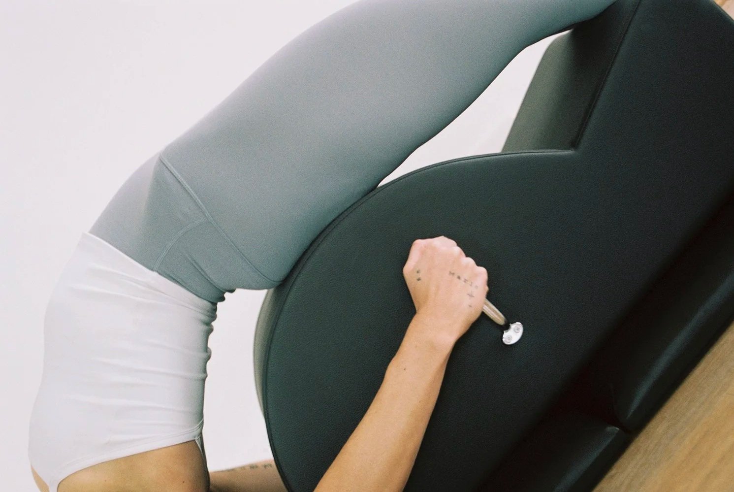 Person leaning forward with their head and upper body on a black massage chair, and their hand holding a key or remote.