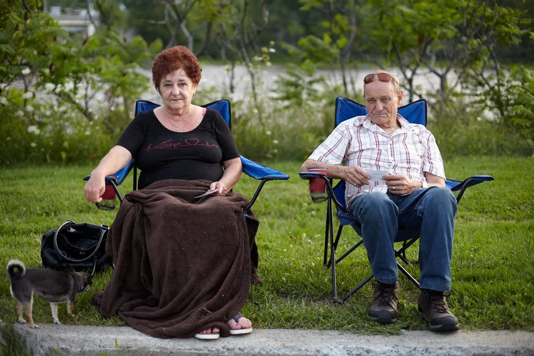 couple-older-fastfood-sitting-outside-grass-river-portrait.jpg
